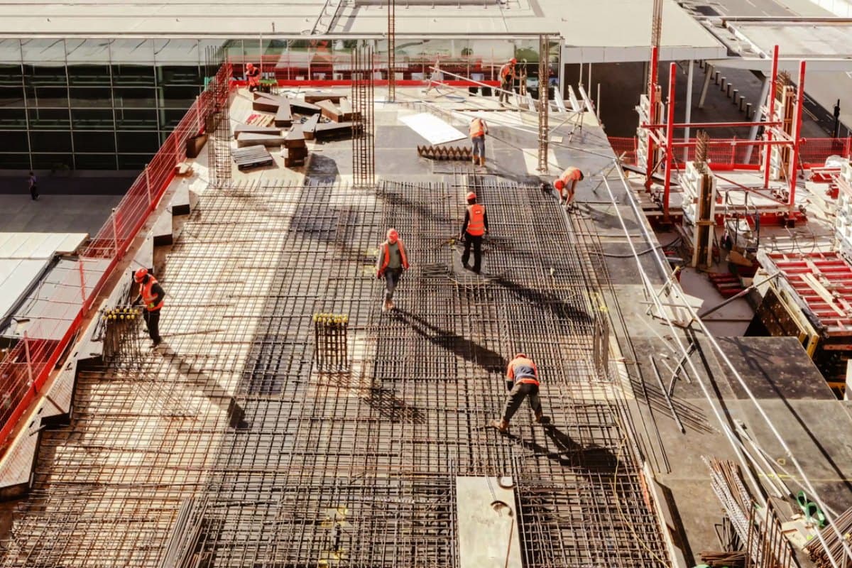 Workers in hard hats and safety vests tying rebar across an elevated deck before a concrete pour