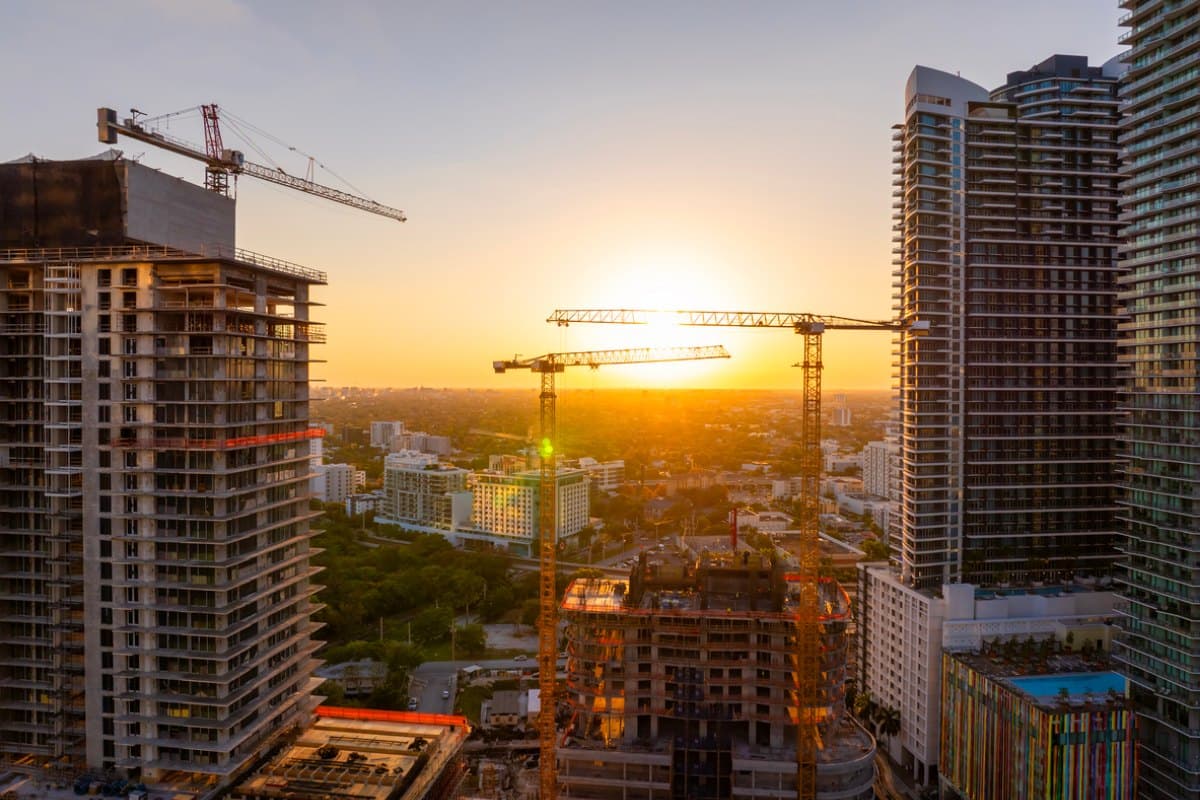 Tower cranes over high-rise buildings under construction at sunset