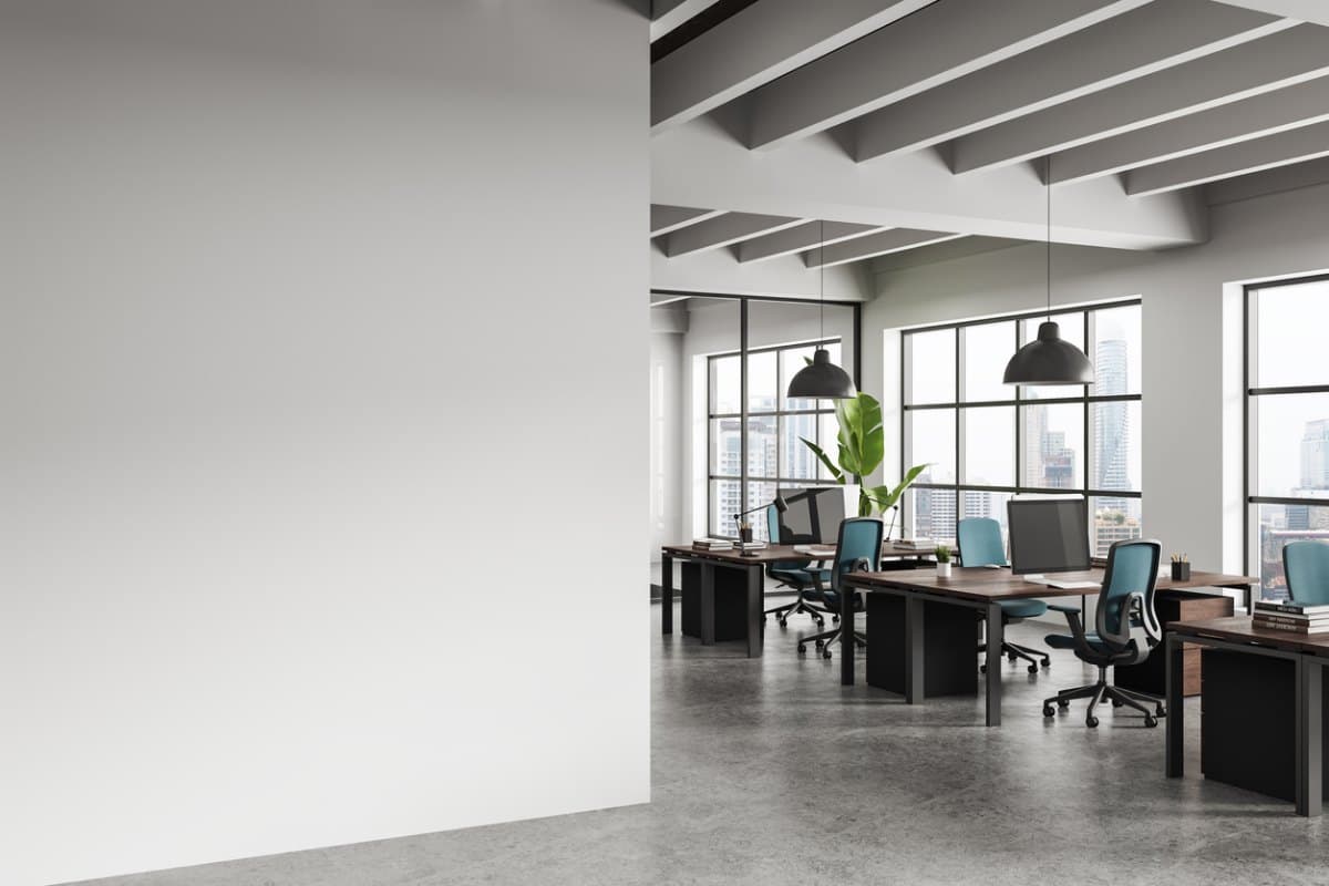 Finished open-plan office interior with desks, blue task chairs, pendant lights and tall windows